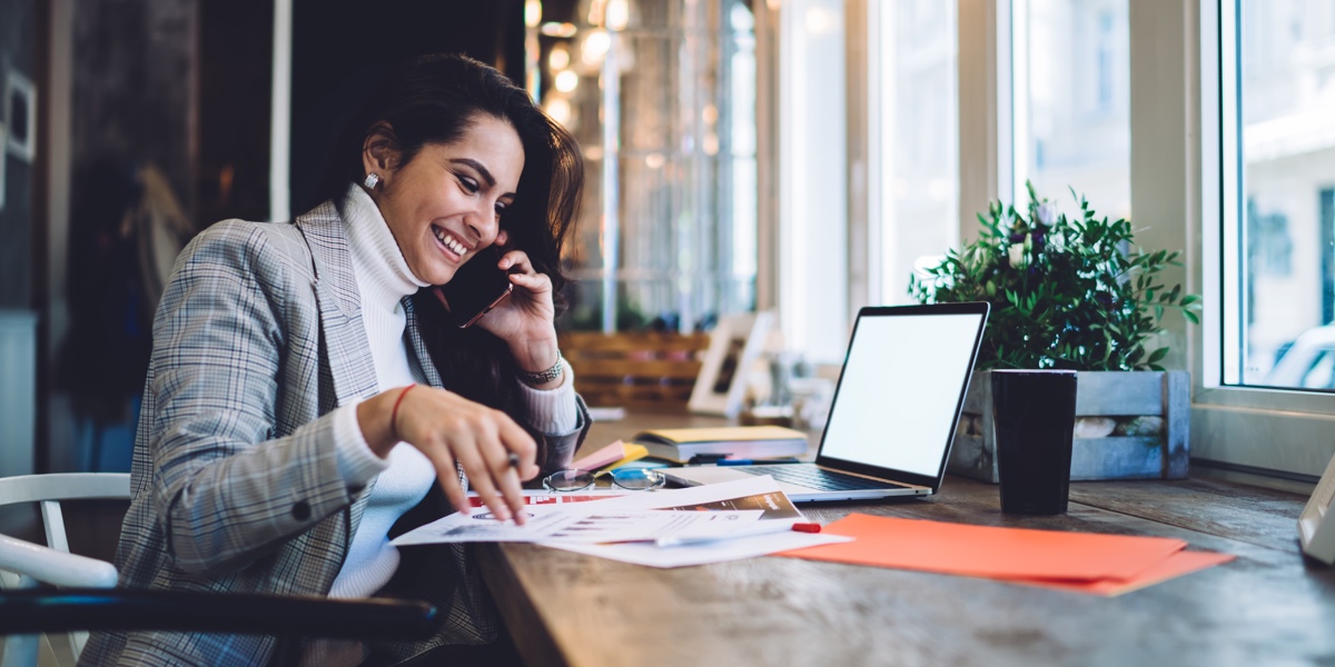 5 Rules to Create a Job-Winning UX Portfolio UX designer sitting at a desk, talking on the phone in front of their laptop