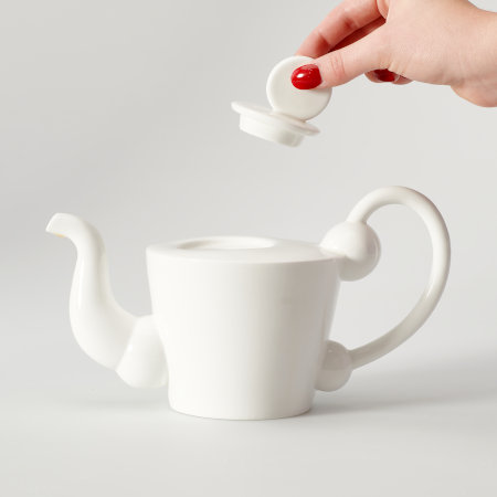 The Denmark teapot with a hand lifting the lid to demonstrate the ease of using the large disk-shaped knob.