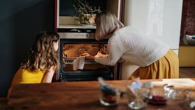 A mother and a child baking using the oven.