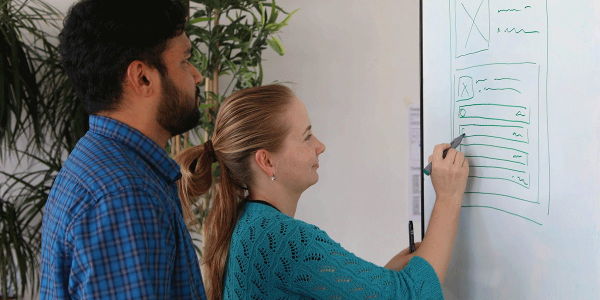 A man and a woman UX designer wireframing using a whiteboard A man and a woman UX designer smiling and wireframing using a whiteboard