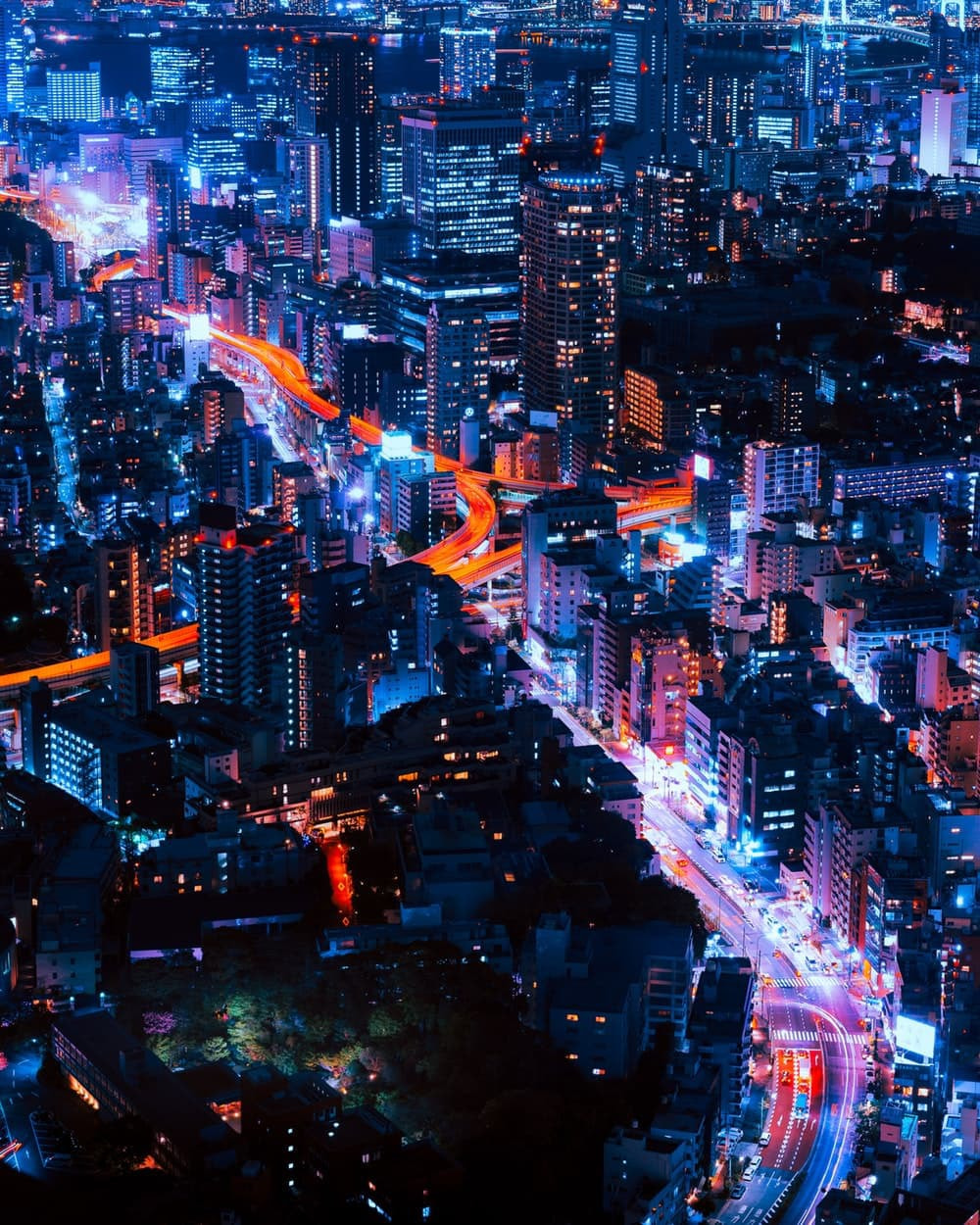 Overview of a vibrant city with strong flourescent colors at night.