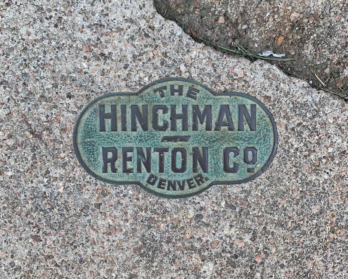 Oxidized metal seal in concrete sidewalk. “The Hinchman Renton Co. Denver.” Undated.