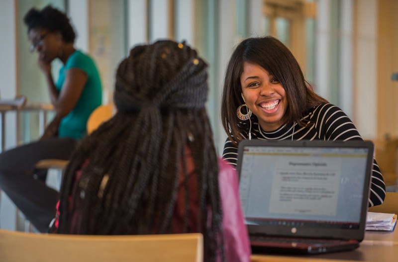 Norfolk State University students smiling working together on their laptops