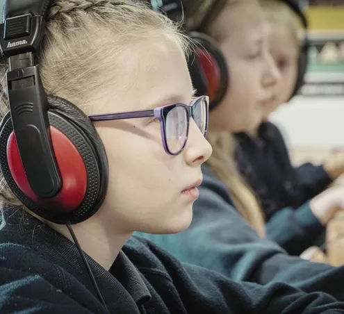 Learners wearing headphones and working on computers at Wath Victoria Prrimary School.