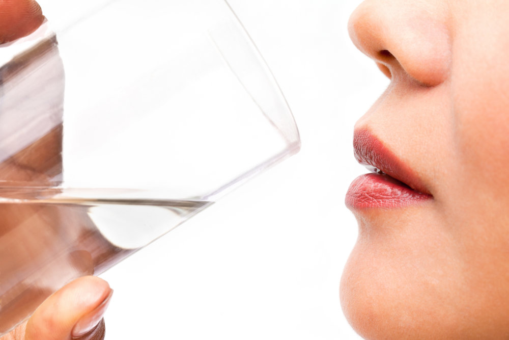 A close-up photo of a woman drinking water.