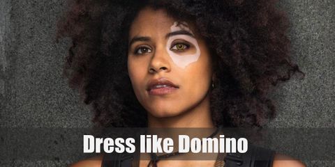 Domino’s appearance in the movie is drastically different from the comics. In the movie, she has beautiful, crazy brunette hair. She wears a sleeveless, black leather top, a pair of black leather pants, and a pair of knee-high boots.