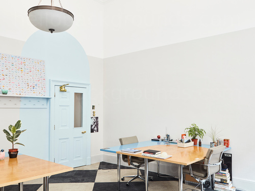 Compact shared workspace with black white chequered flooring and wooden table with metal framed padded chairs  Google Meet background