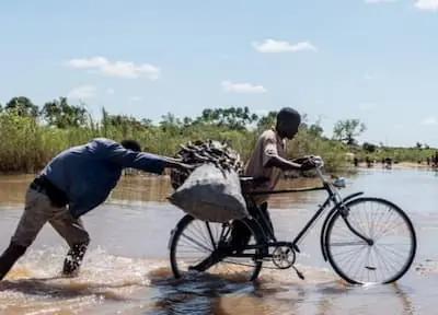 Joze Paulino and Gomez Dies push a bicycle loaded with charcoal across a flooded river near Nhamatanda, Mozambique.