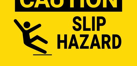 Black text on bright yellow sign,
Caution, slip hazard,
with stick figure falling backwards.
