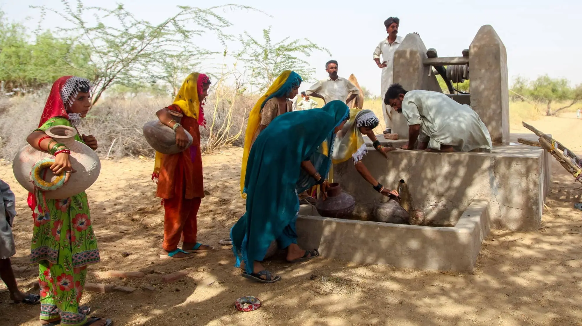 Women fetch water at a dug well