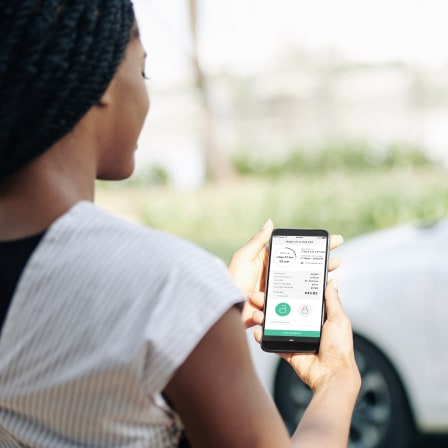 Back of woman looking at a car rental app on her smartphone