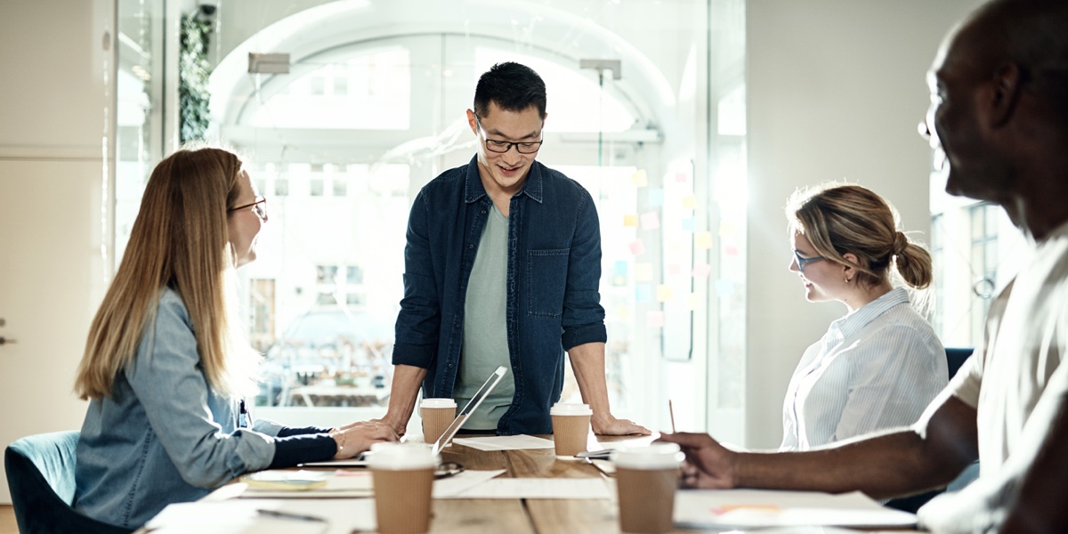 UX Designer’s Guide: How and When to Ask for a Raise UX designer standing at the head of a table, pitching members of the team for a raise in salary