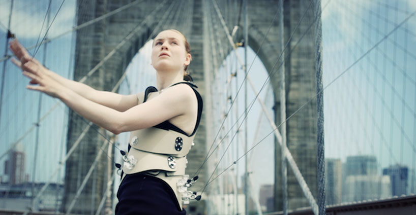 Another medium shot of a woman "playing" the Brooklyn Bridge with her own stringed interface.