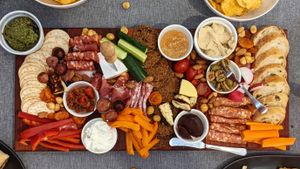 Photo of a grazing platter crammed full of various smoked meats, cheeses, dips, crackers and vegetable sticks