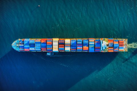 Overhead view of a cargo ship in water
loaded with multi-colored shipping containers.
