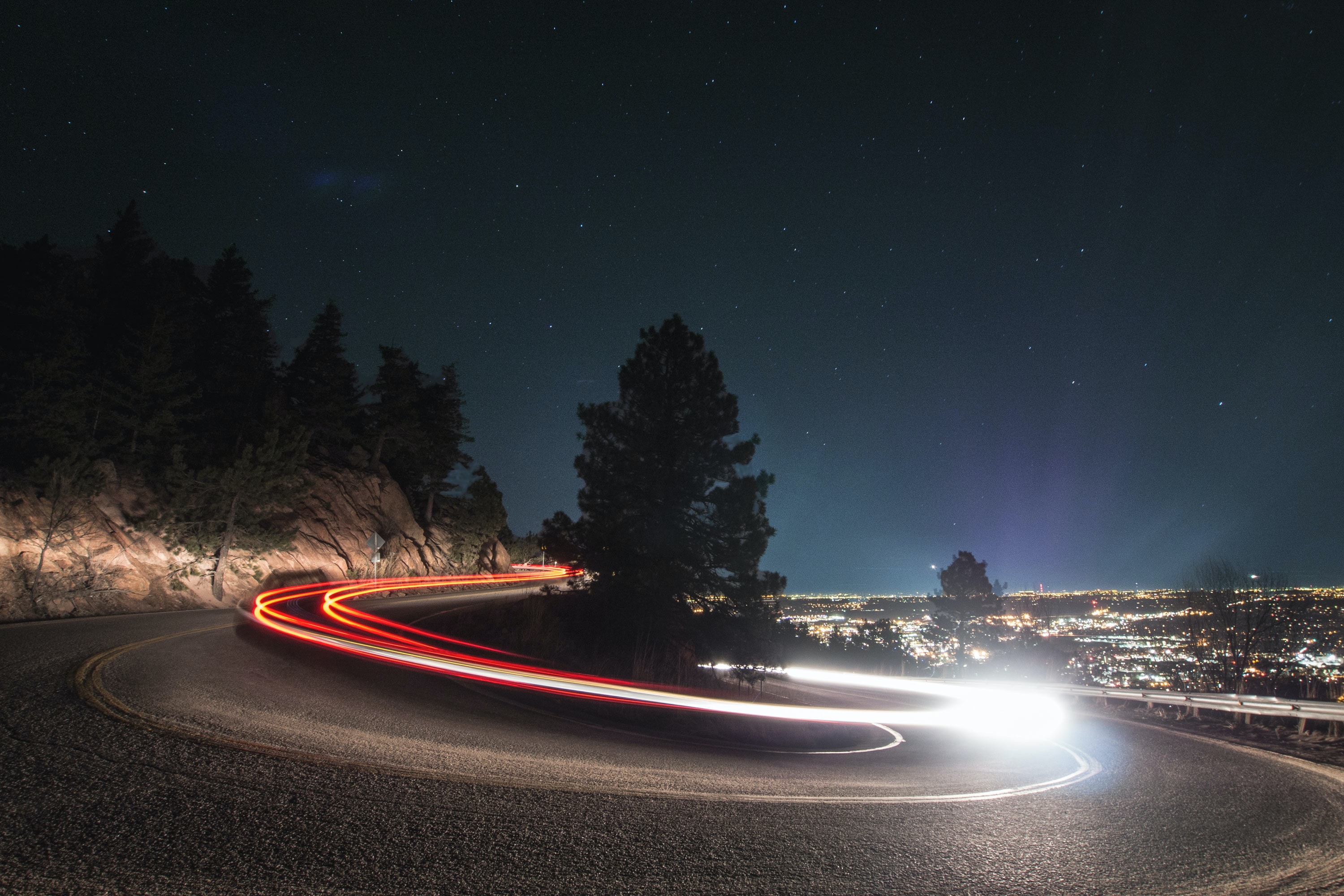 timelapse of car tail lights around road bend at night