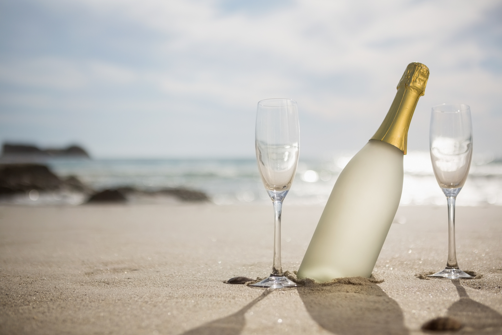 bouteille de champagne dépoli et ses flutes sur la plage