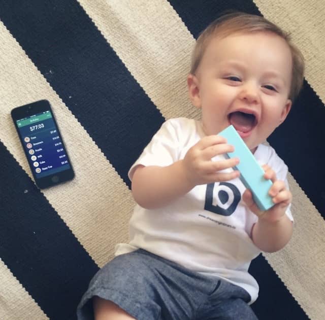 A baby boy next to an iPhone on a rug.