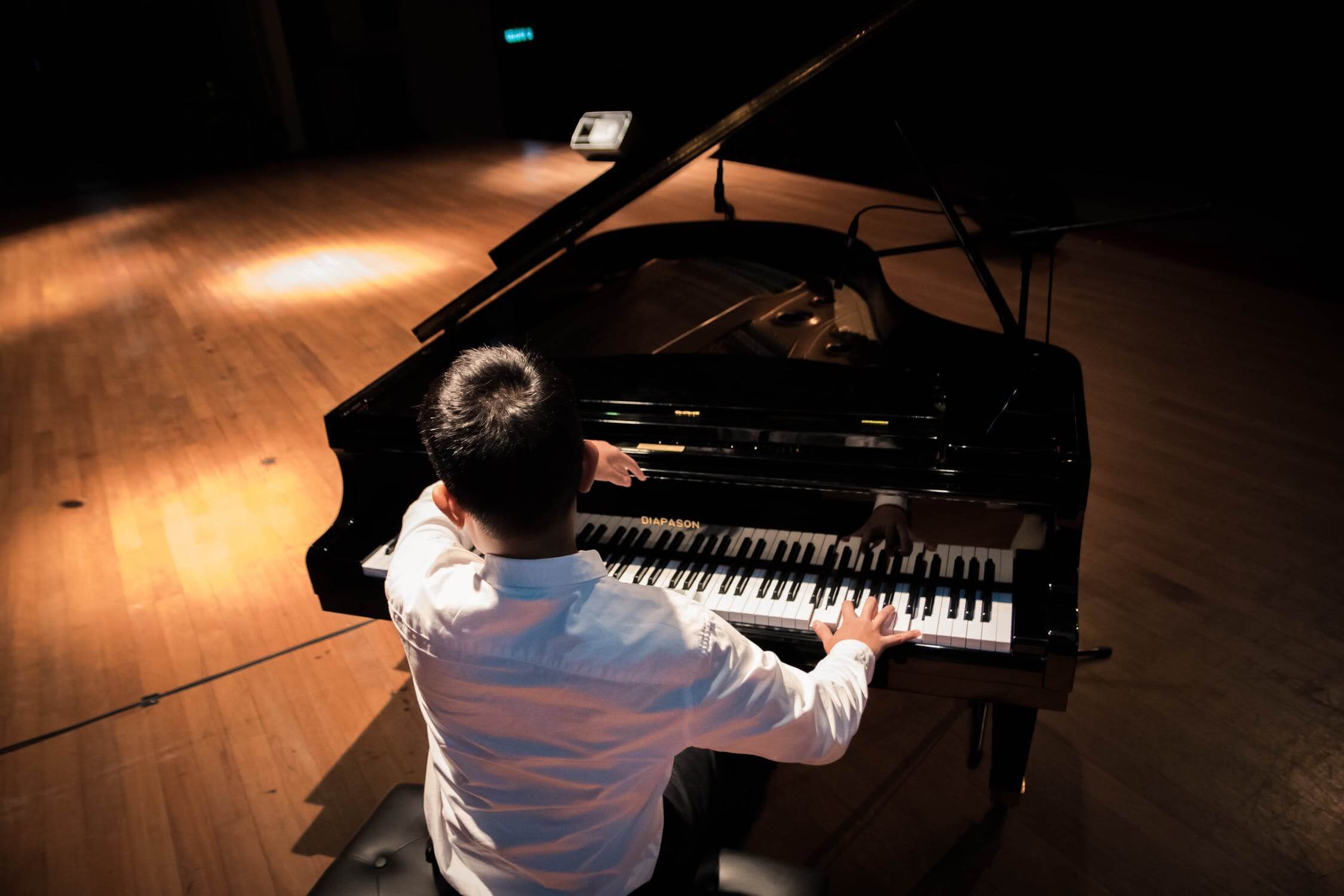 man in white shirt, seated playing piano