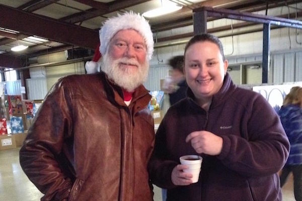 Burr Datz in a Santa hat on the left and Katherine Brinkley, on the right, smile for the camera.