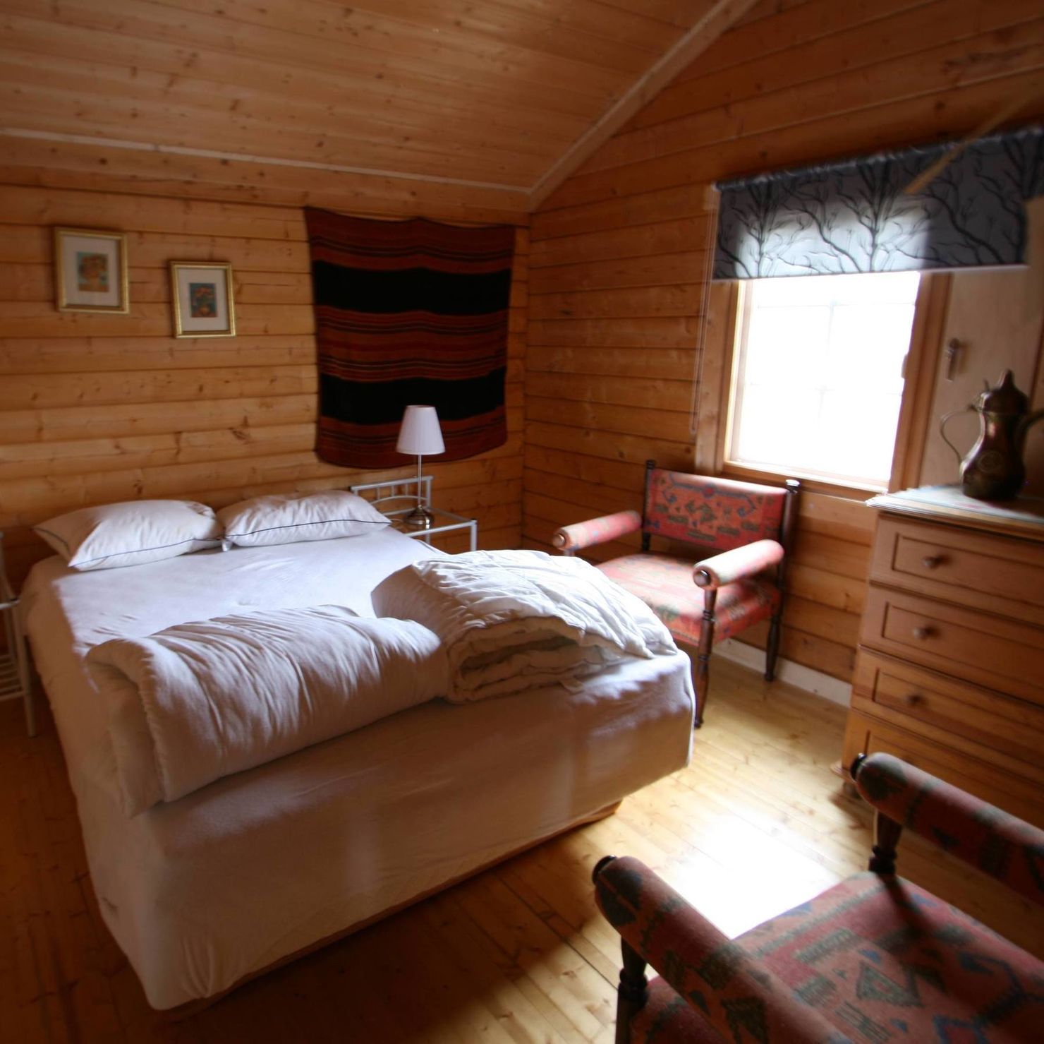 Geräumiges Schlafzimmer mit Fenster, Doppelbett, Sessel und Kommode