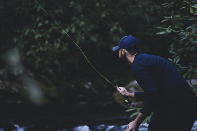 Shallow focus photography of man fly fishing