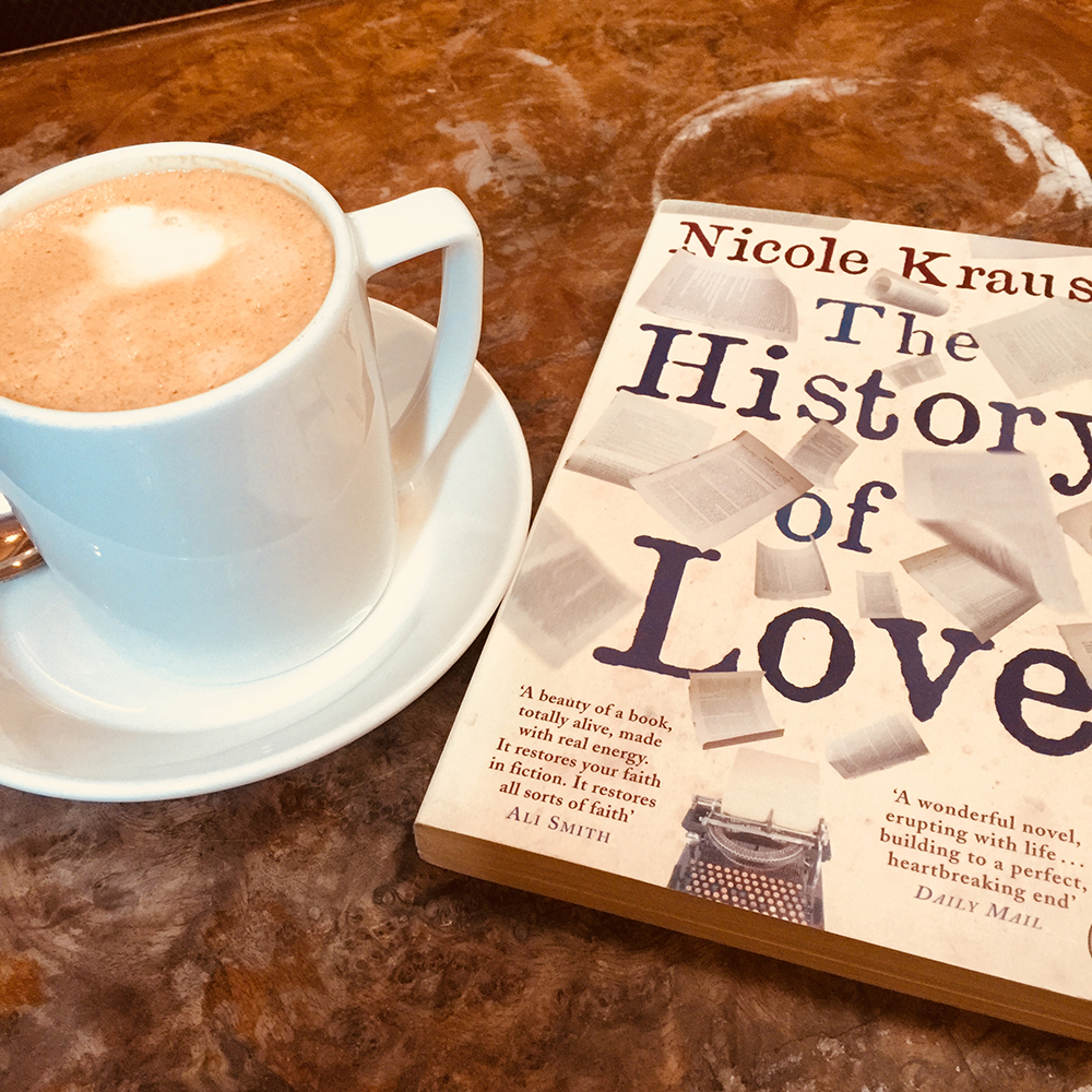 the book The History of Love with a cup of coffee