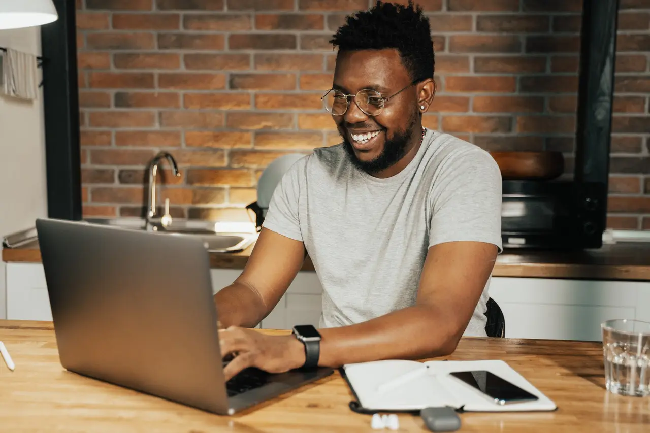 Man sitting in front of his laptop smiling.