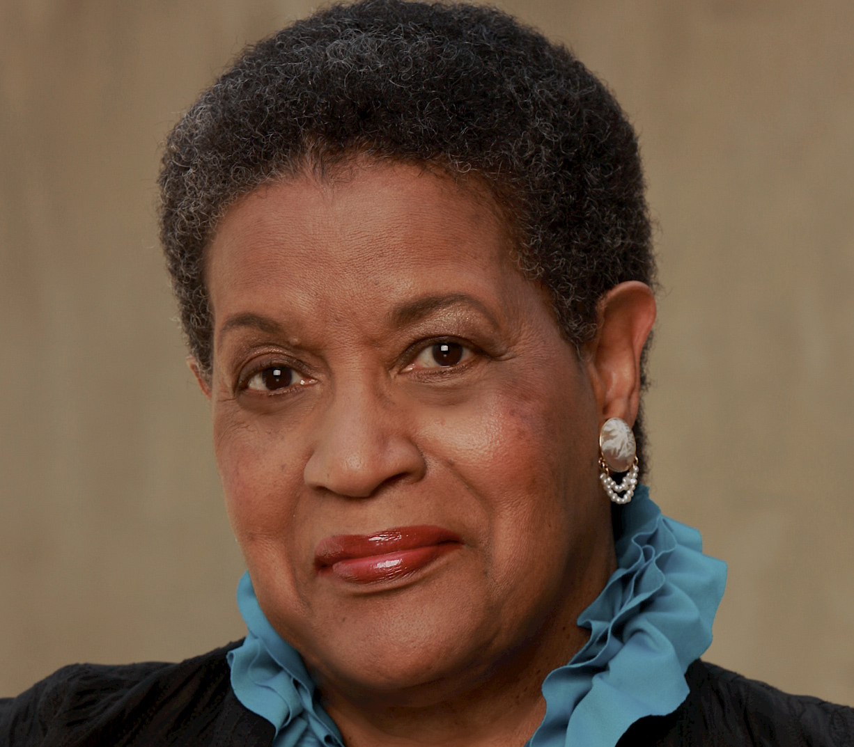 A photo of Myrlie Evers wearing a blue ruffled collared shirt.