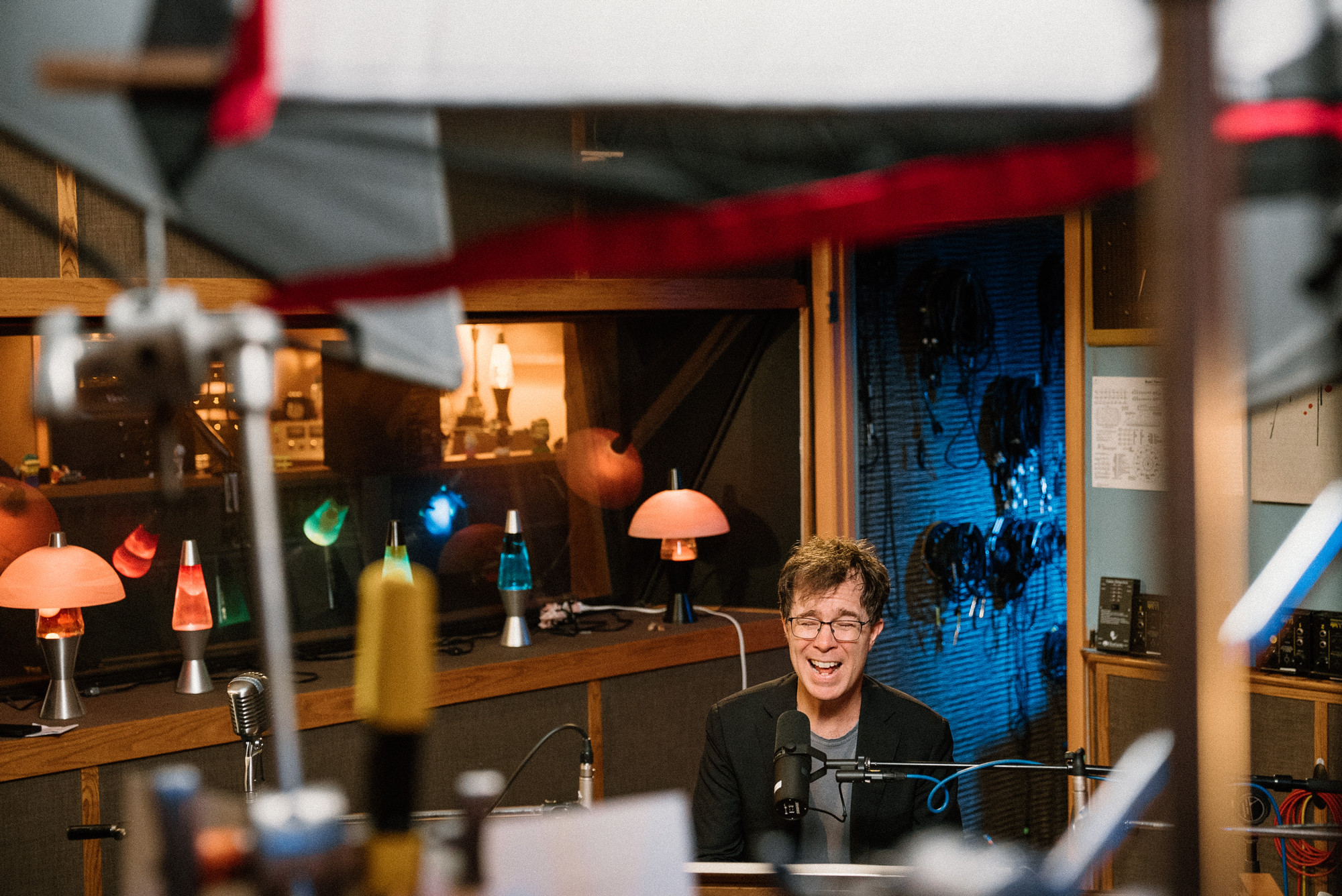 Ben Folds singing in a studio with lava lamps and equipment surrounding him.