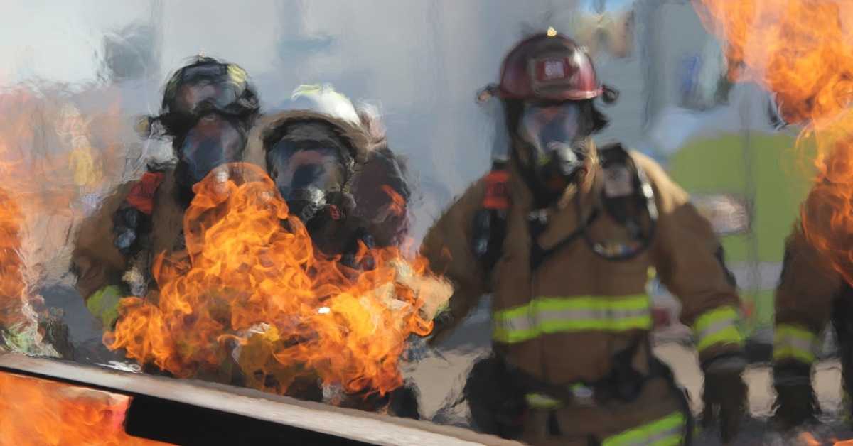 Drei Feuerwehrleute in der Feuerwehr Grundausbildung üben das Löschen von Bränden