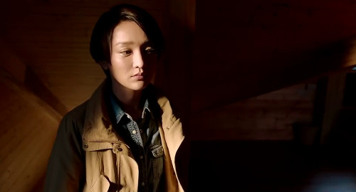 A screenshot from the movie 'Women Who Flirt' of Zhou Xun's character, Angie, solemnly looking around a dimly lit room.