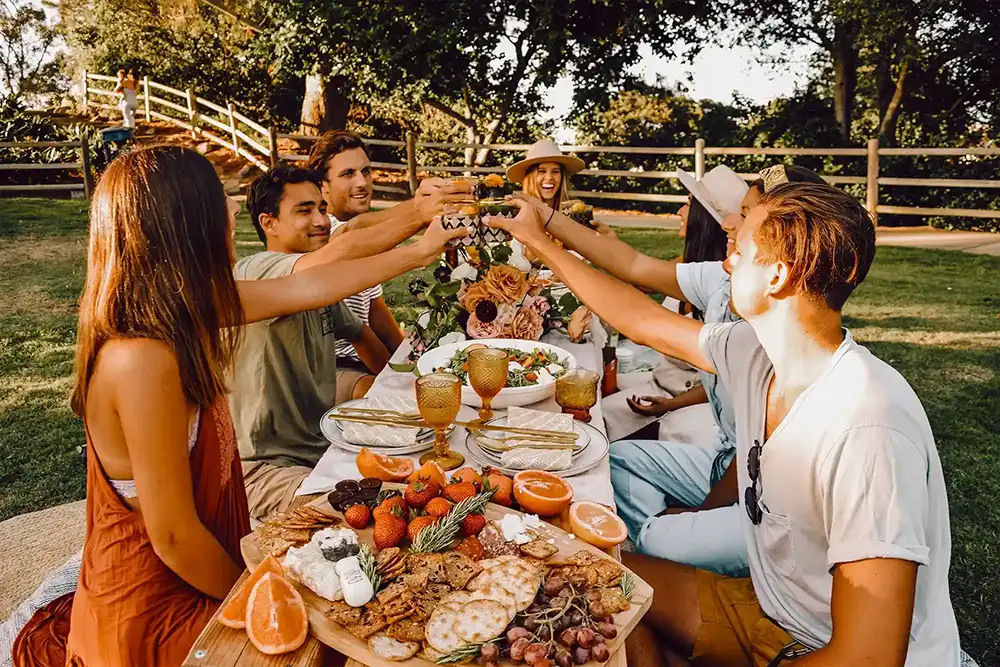 Large group of friends at a long table with trays of food outside