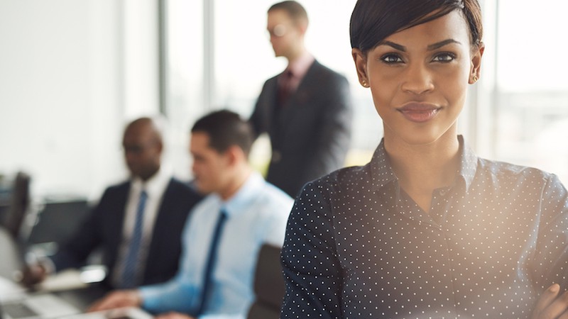 Grinning business owner in front of group of employees at conference table
