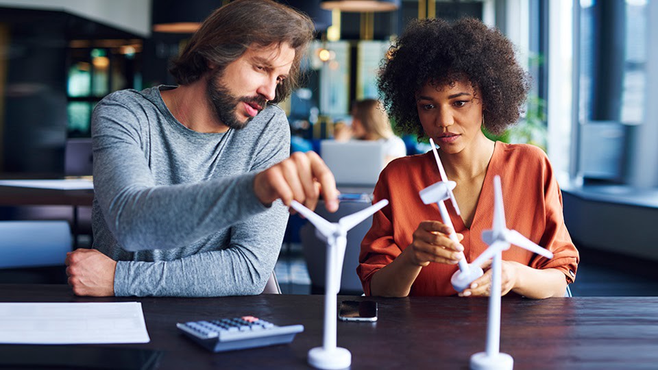 Male and female social workers examining miniature windmills.
