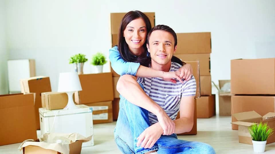young couple in new home surrounded by packaging boxes
