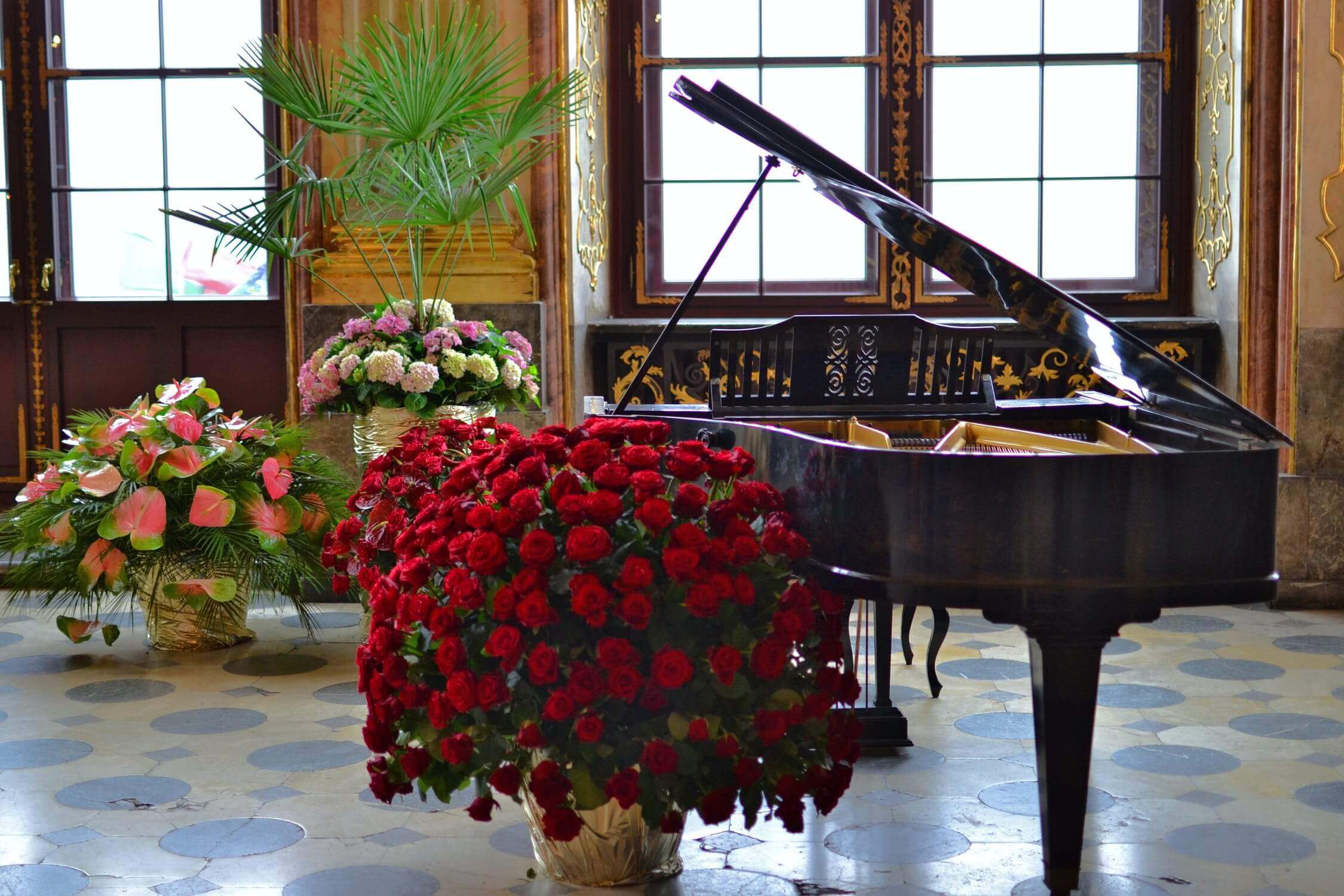 Piano in an ornate setting surrounded by flowers