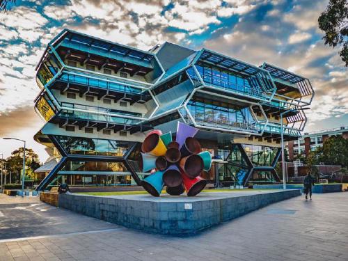 Thumbnail A colorful metal sculpture in fron of a modern building with 2 hexagonal floors