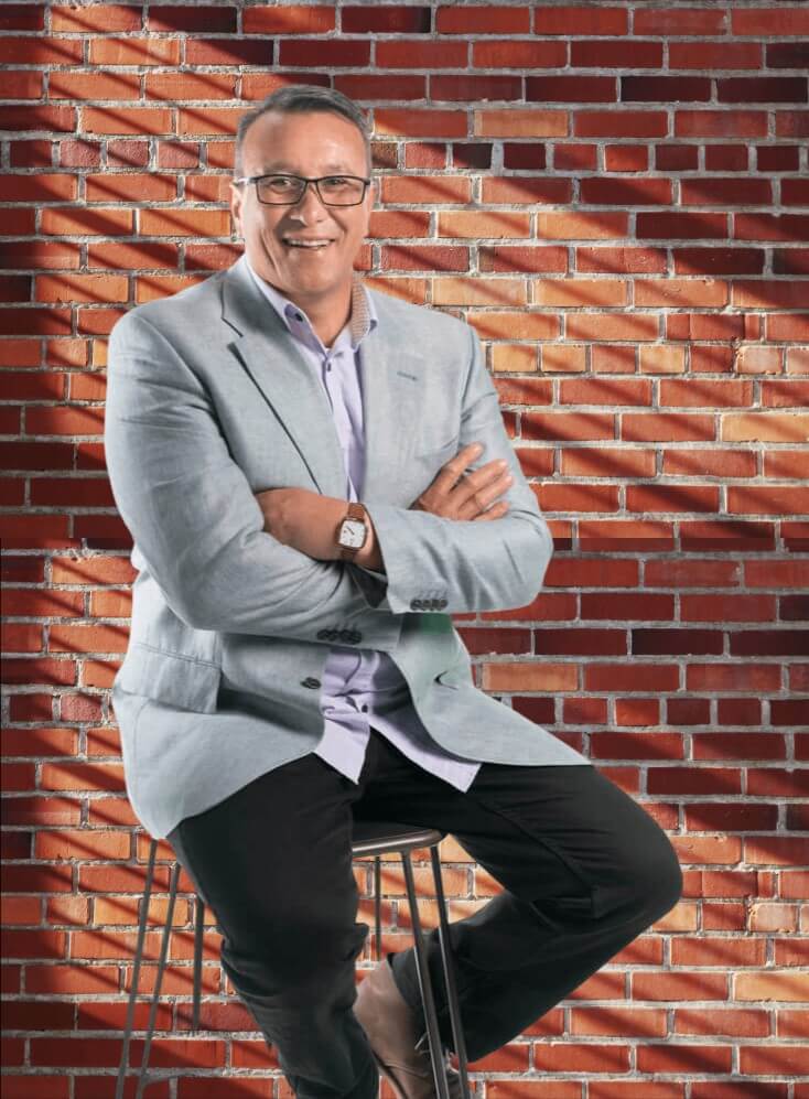 Man sitting on a stool, brick background