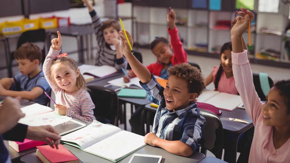 Children in class. Some of them have their hands raised