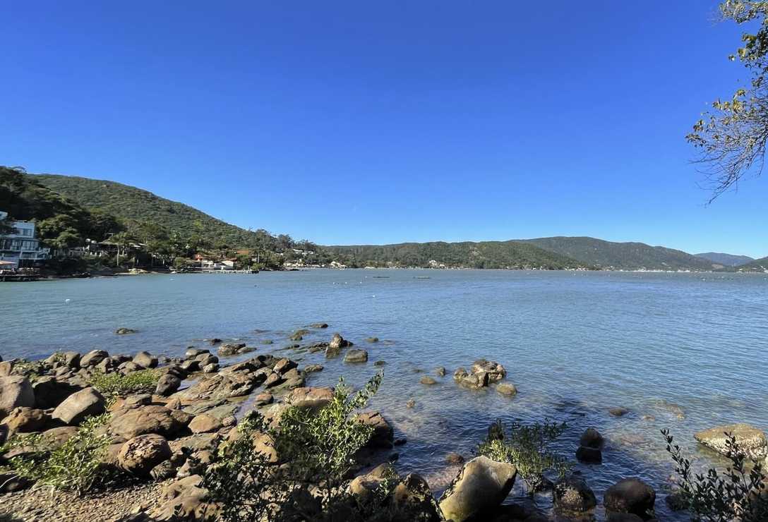 Vista da água com pedras na areia e no inicio da água