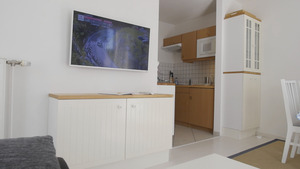 Andere Wohnzimmeransicht mit Fernseher, Sicht auf Küche und Kommode