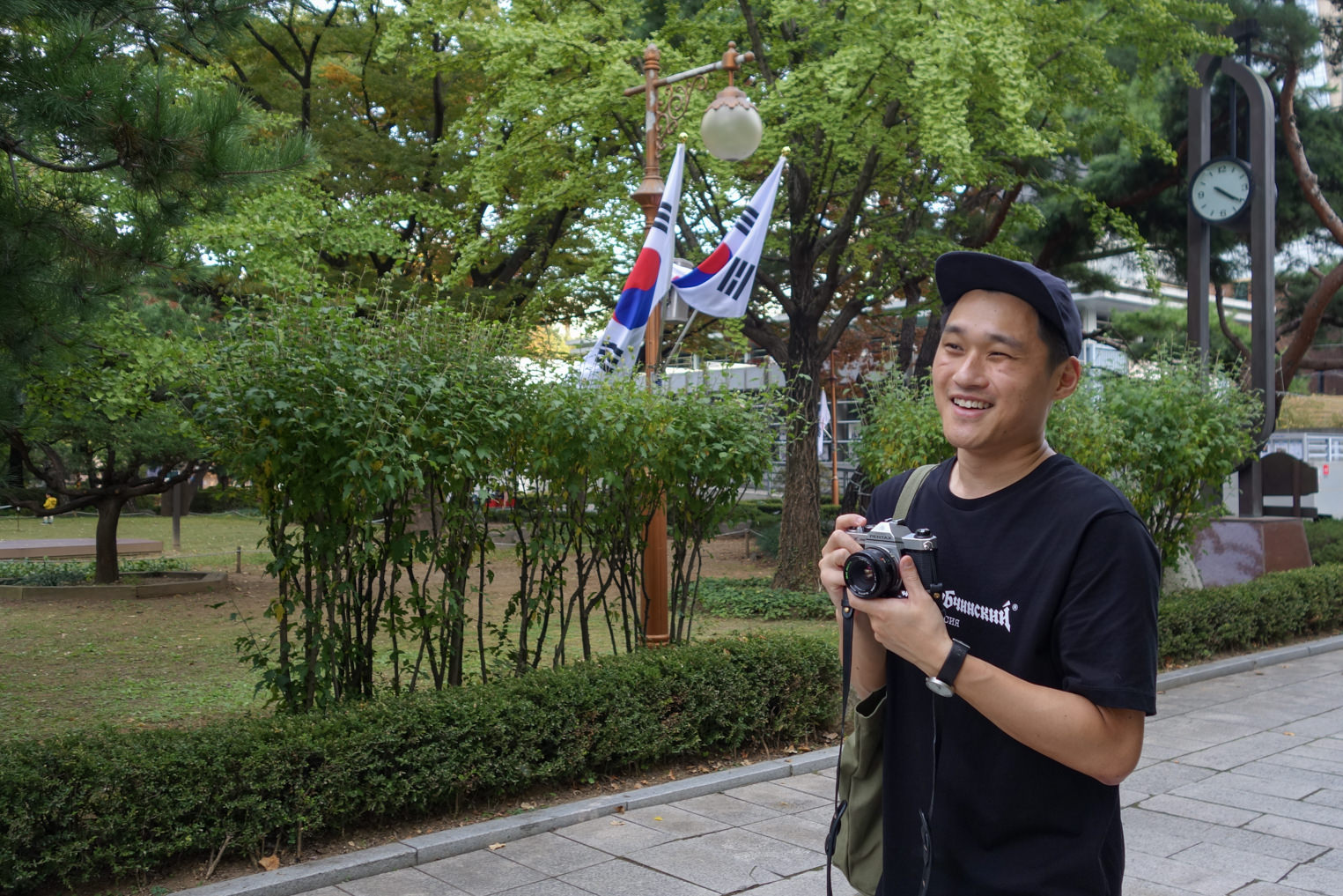 A photo of me, smiling, holding my camera on a trip to Seoul in 2018