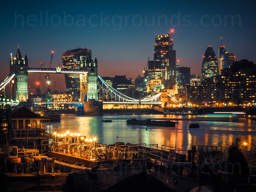 Tower Bridge lit up at night over river Thames amongst urban cityscape reflected on the water  Skype background