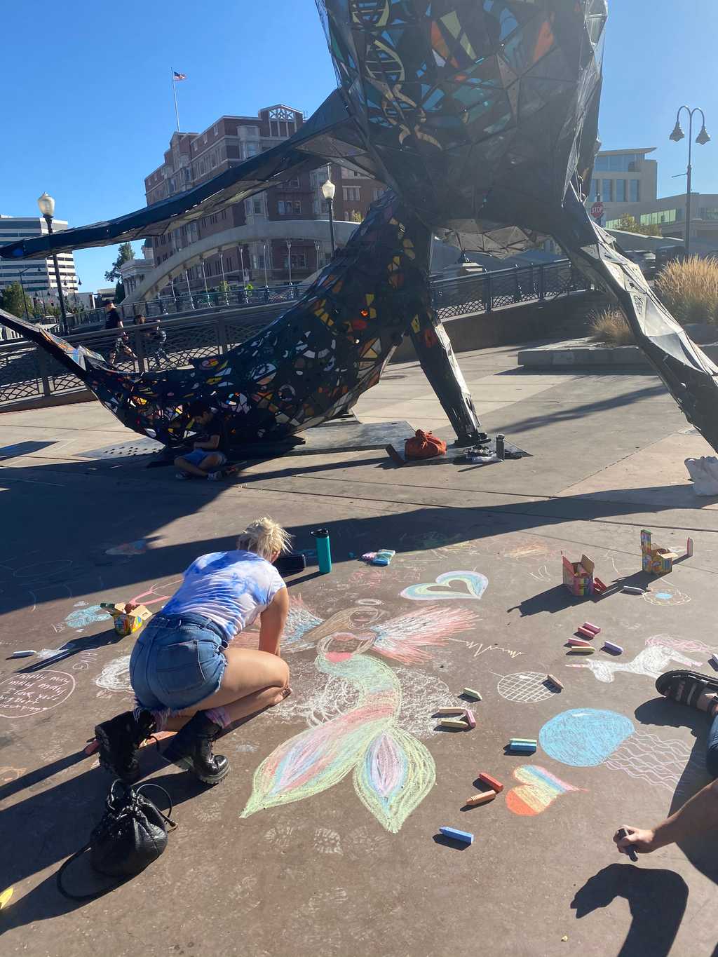 Reighan drawing in chalk next to a mermaid angel