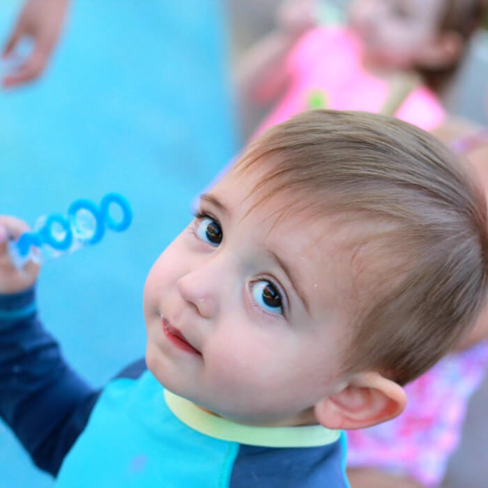 Baby holding bubble wand.