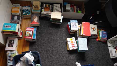 Many books, sitting in piles on the floor