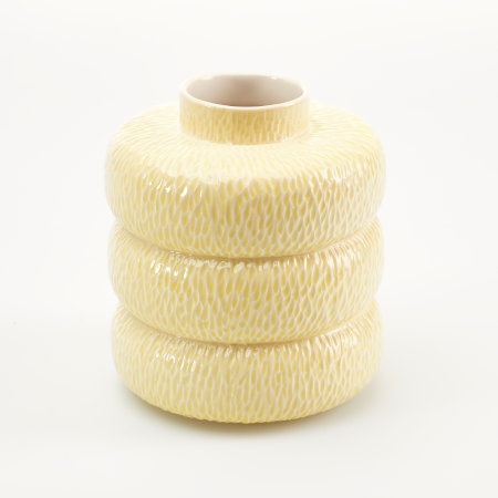 A yellow vessel made up of three donut-shaped sections and a short neck, with an all over incised texture that holds the yellow glaze more intensely.