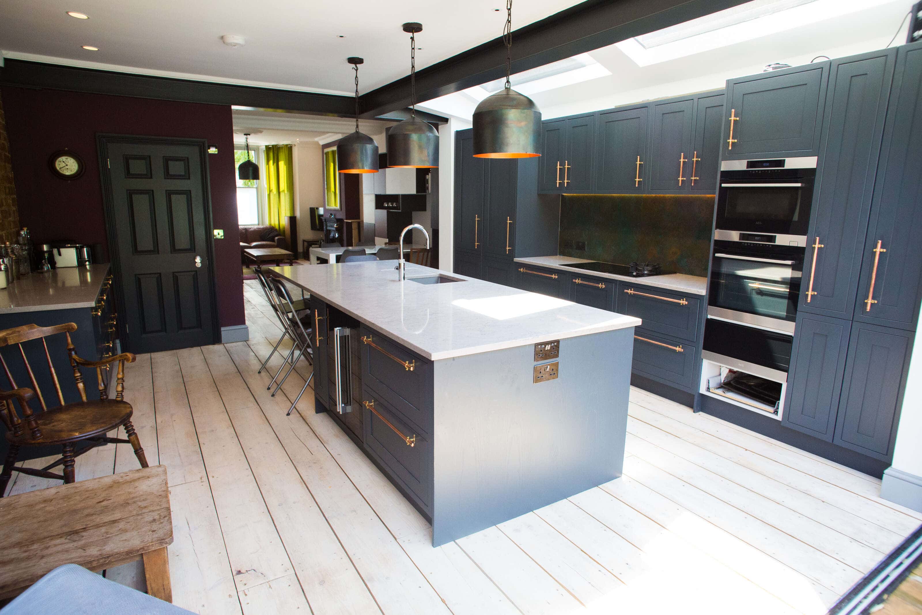Looking through the Railings (bluey grey) shaker kitchen with copper handles with grey stone top through to the lounge.