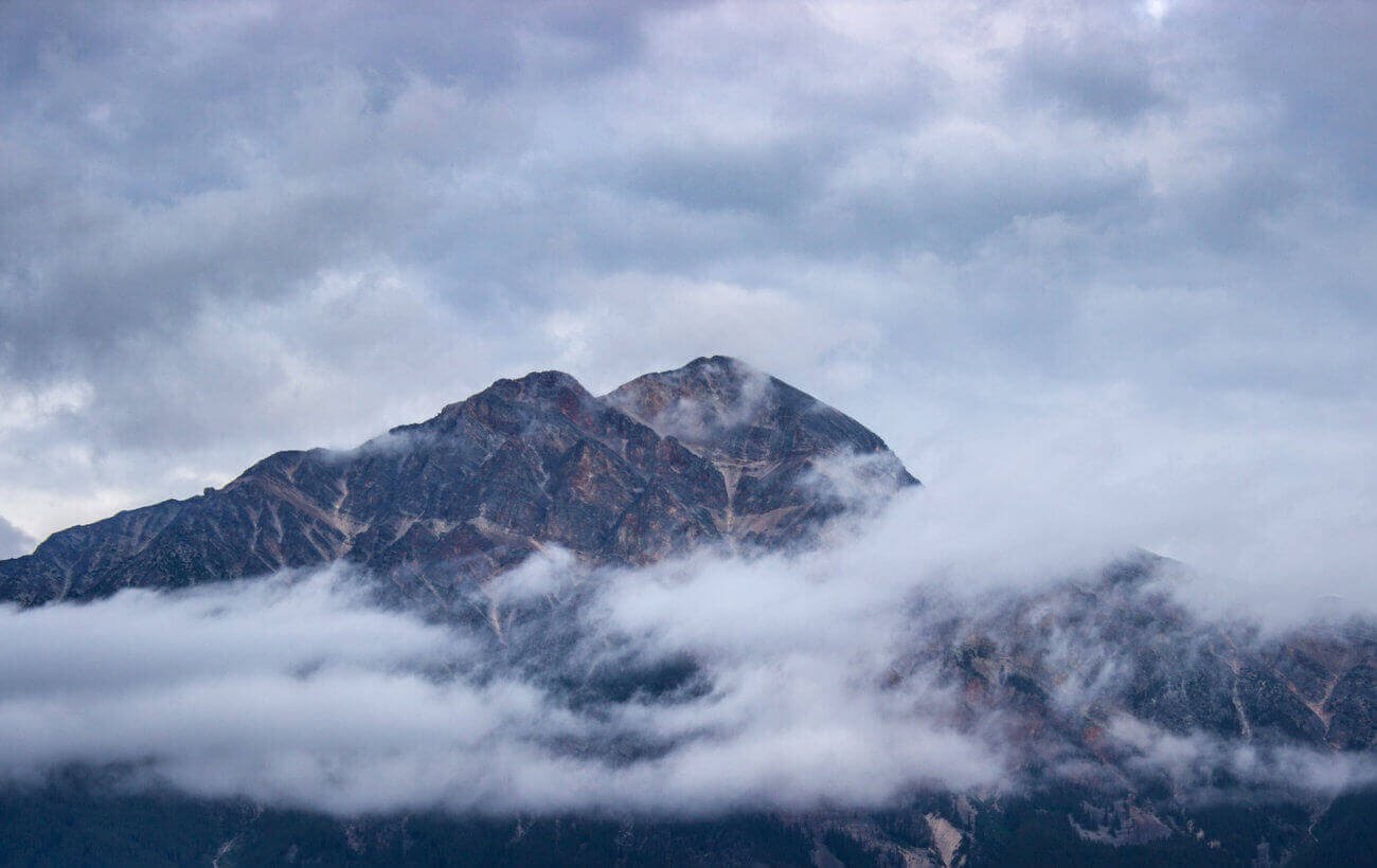 Uma montanha com algumas nuvens cobrindo partes dela